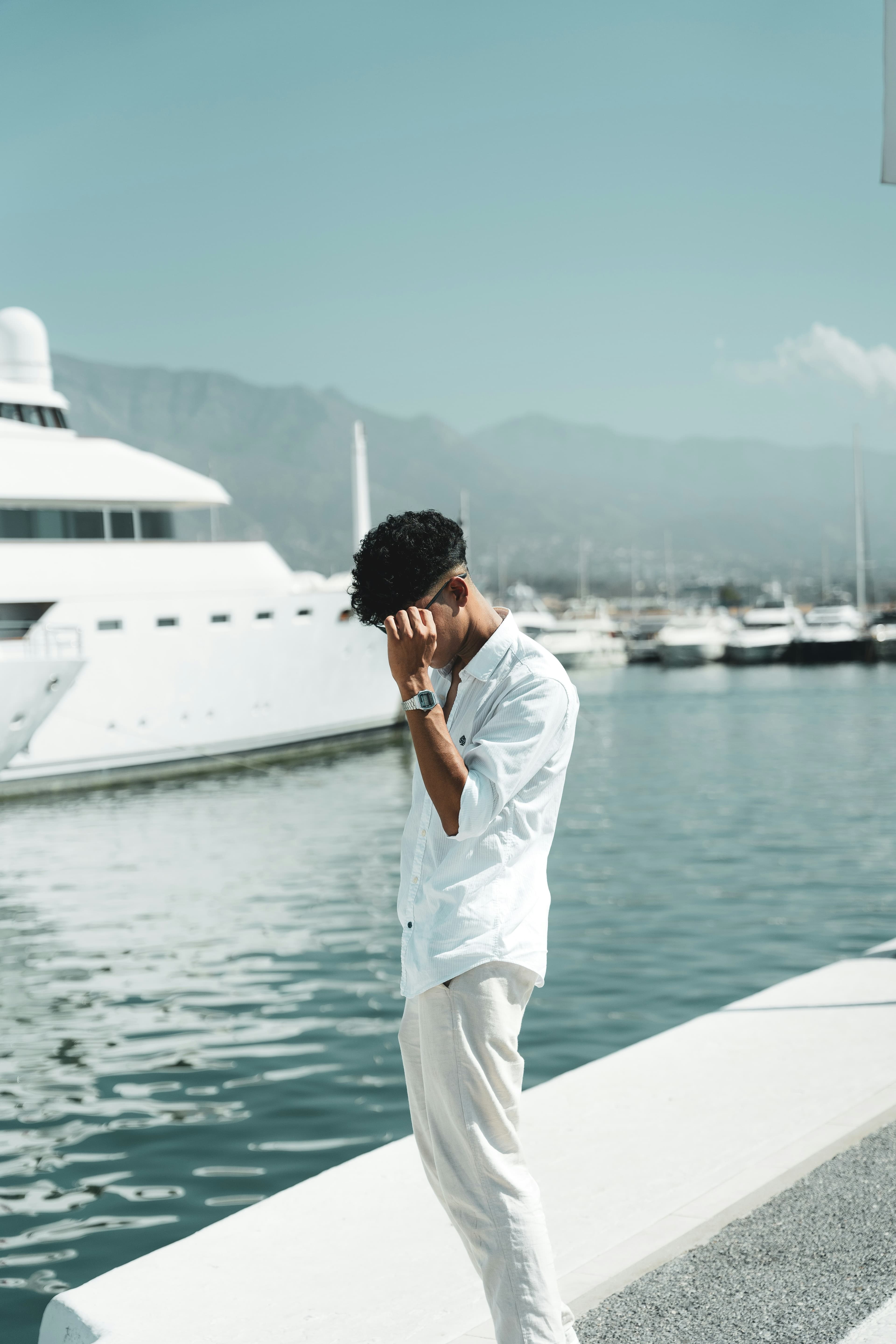 Man on the phone at a marina beside a yacht
