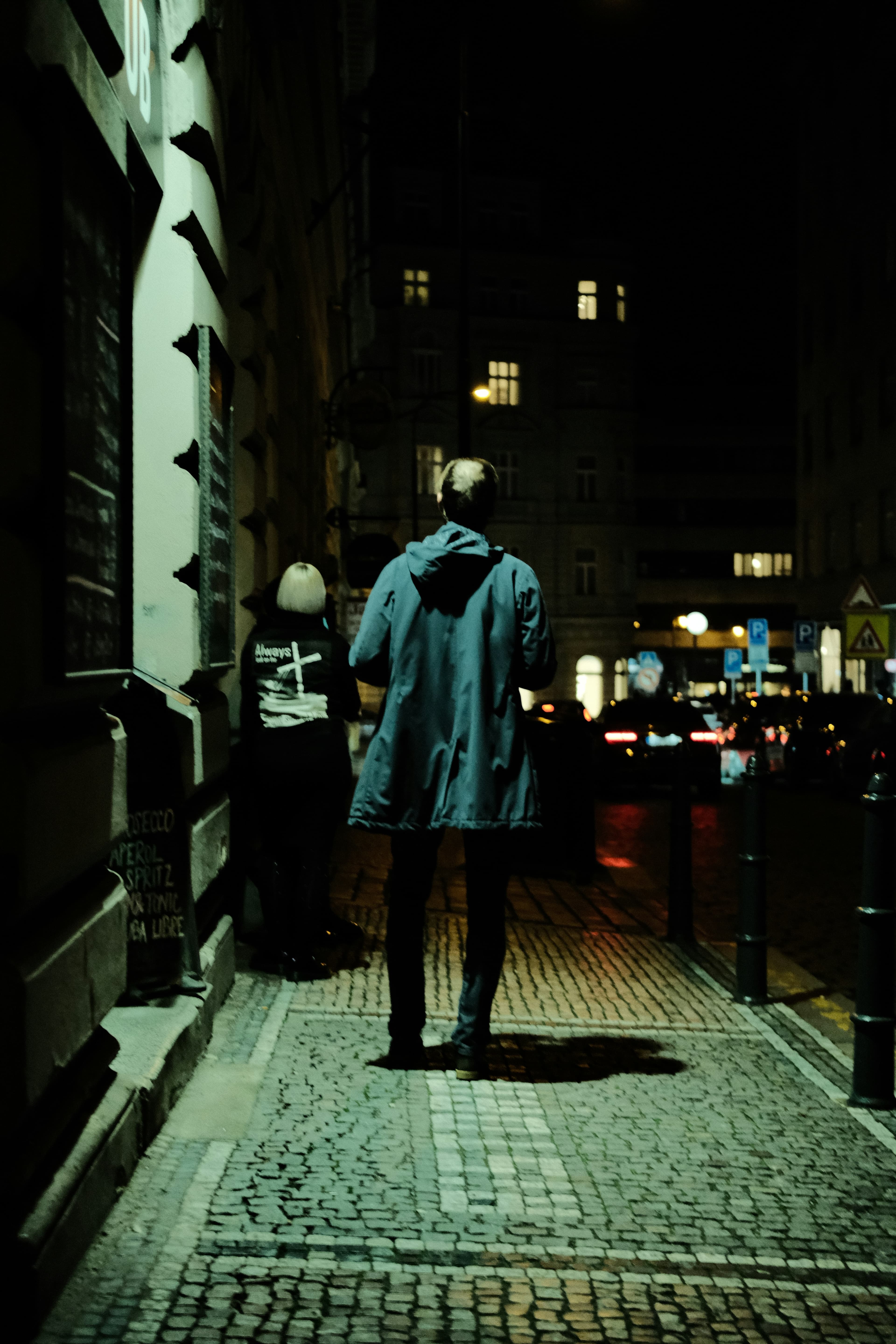 Person in a coat on a cobblestone street at night
